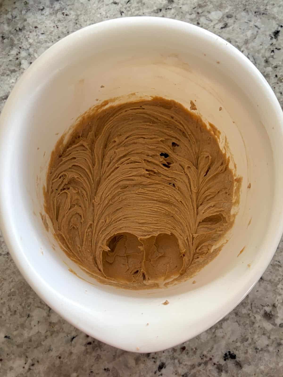 Peanut butter being mixed into the sugar mixture in a bowl.