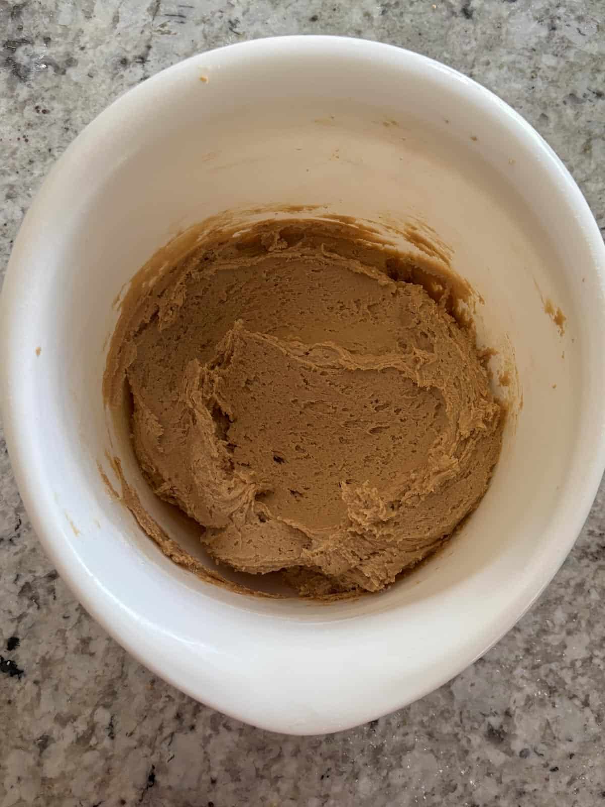 Peanut butter cookie dough in a bowl on the counter.