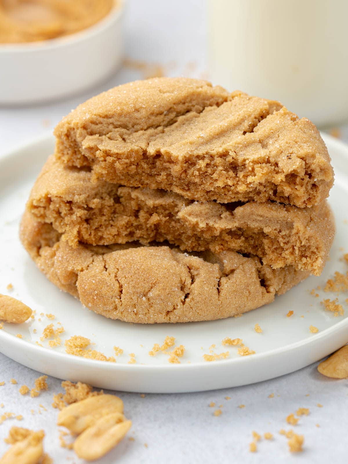 A stack of cookies on top of each other on a plate with peanuts around.
