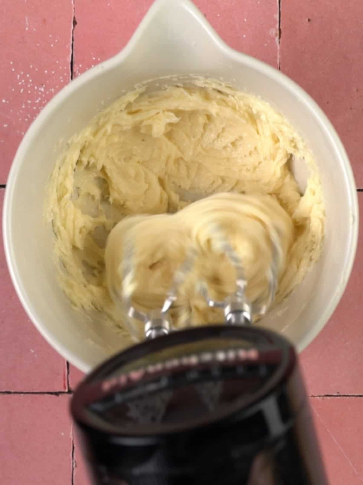 Butter and sugars being mixed together until light and fluffy in a bowl.