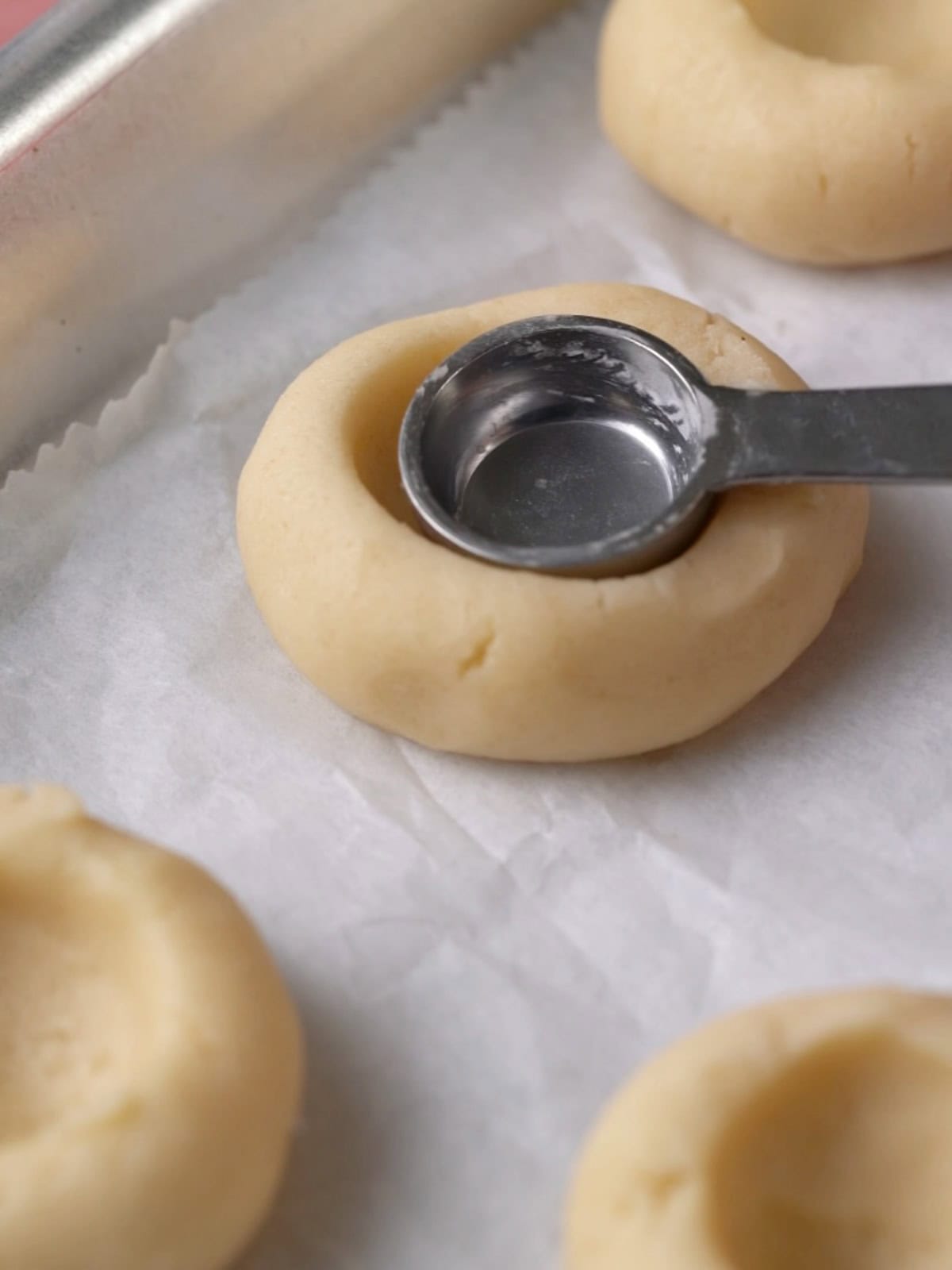 Pushing an indent into the cookie dough to create space for the jam.