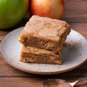 Apple blondies with cinnamon and apples on a plate stacked.