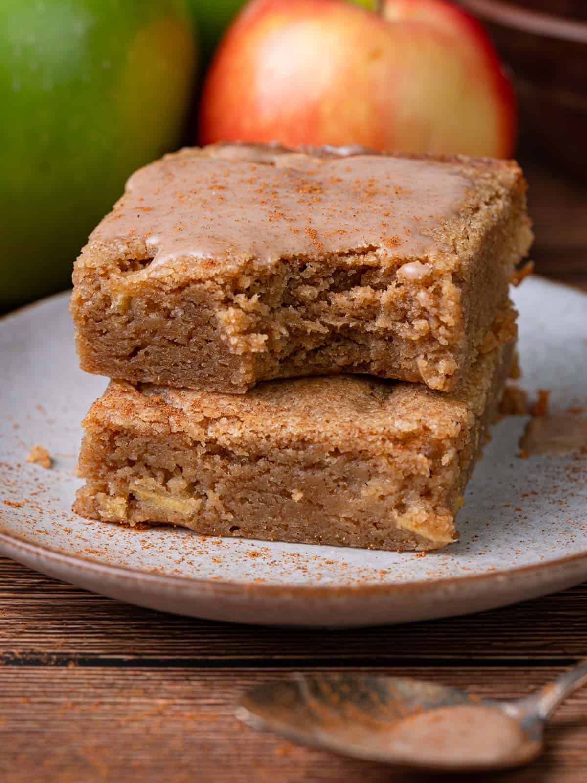 A bite taken out of the blondie on top of another with apples.