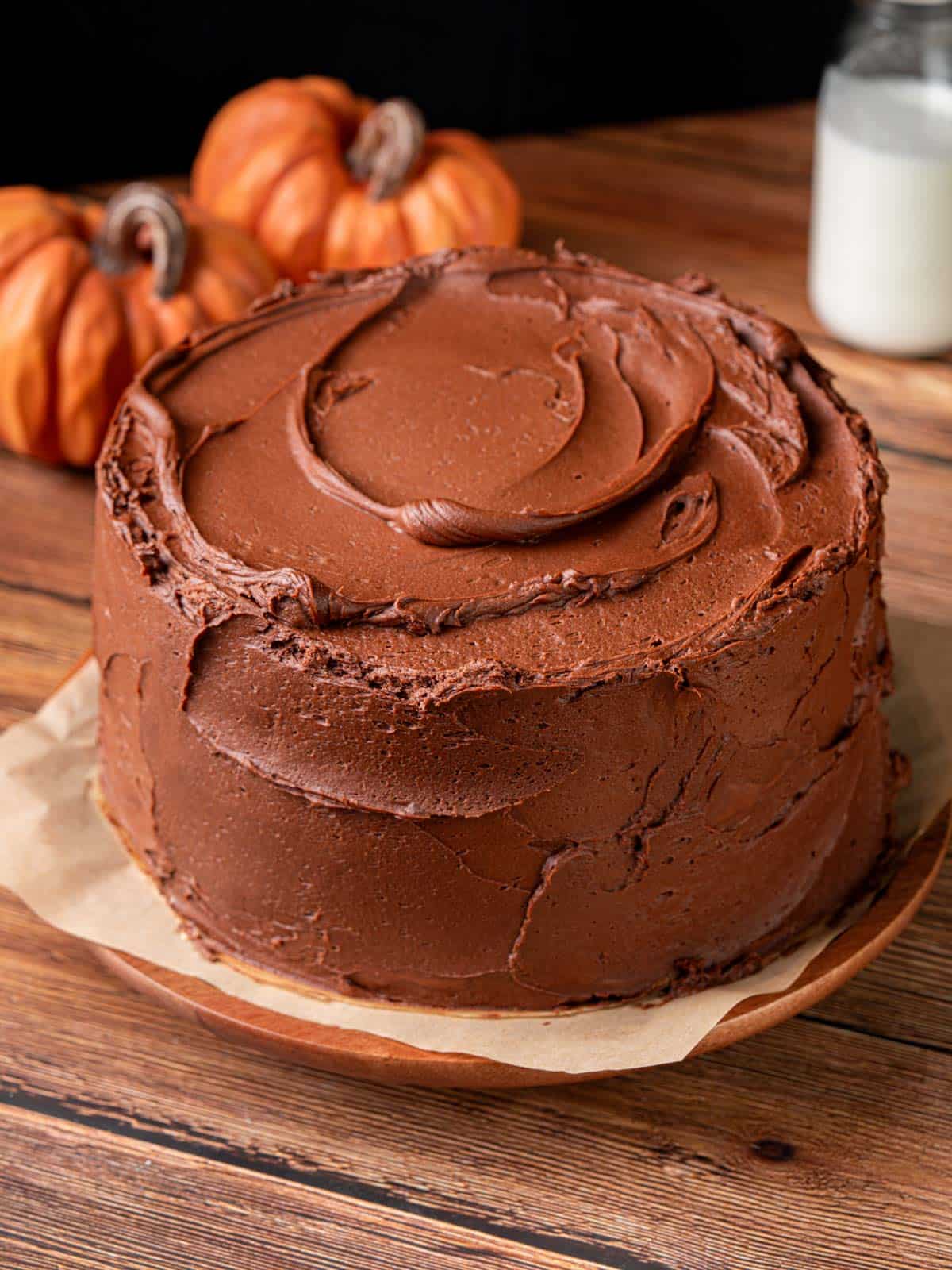 A layered cake with chocolate frosting on the outside on a cake stand.