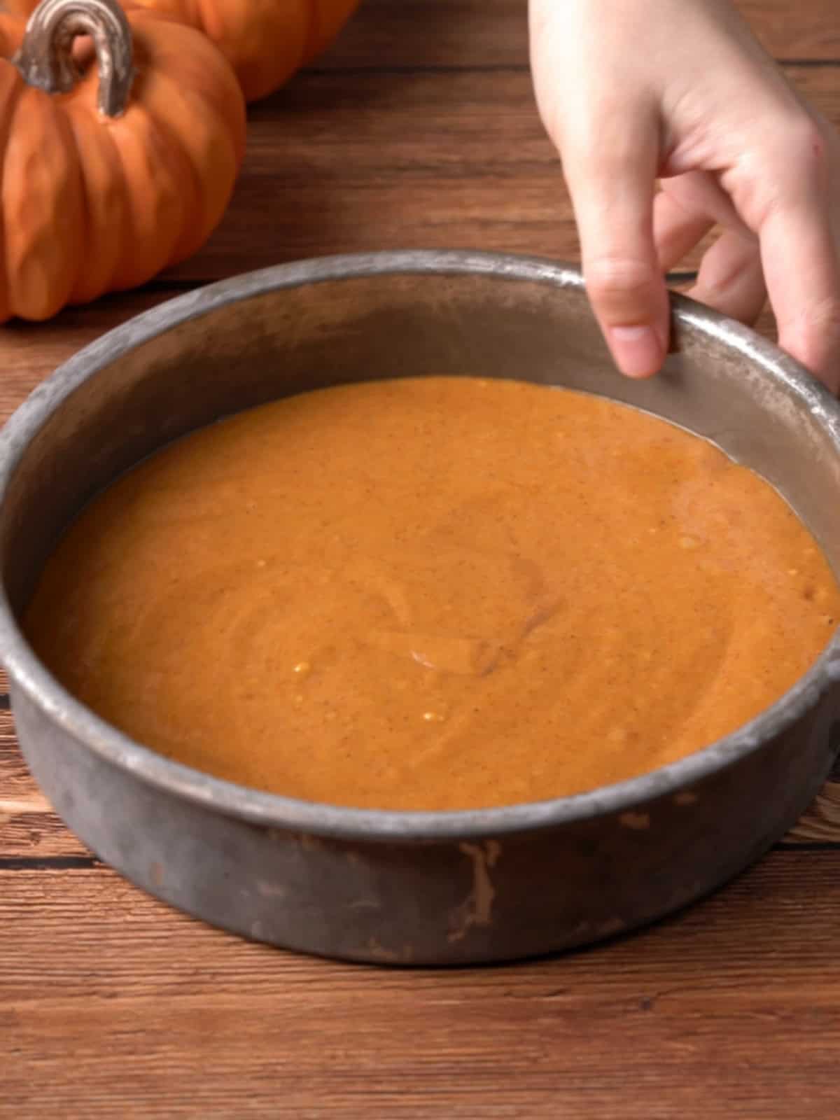 Pumpkin cake batter in an 8 inch cake pan.