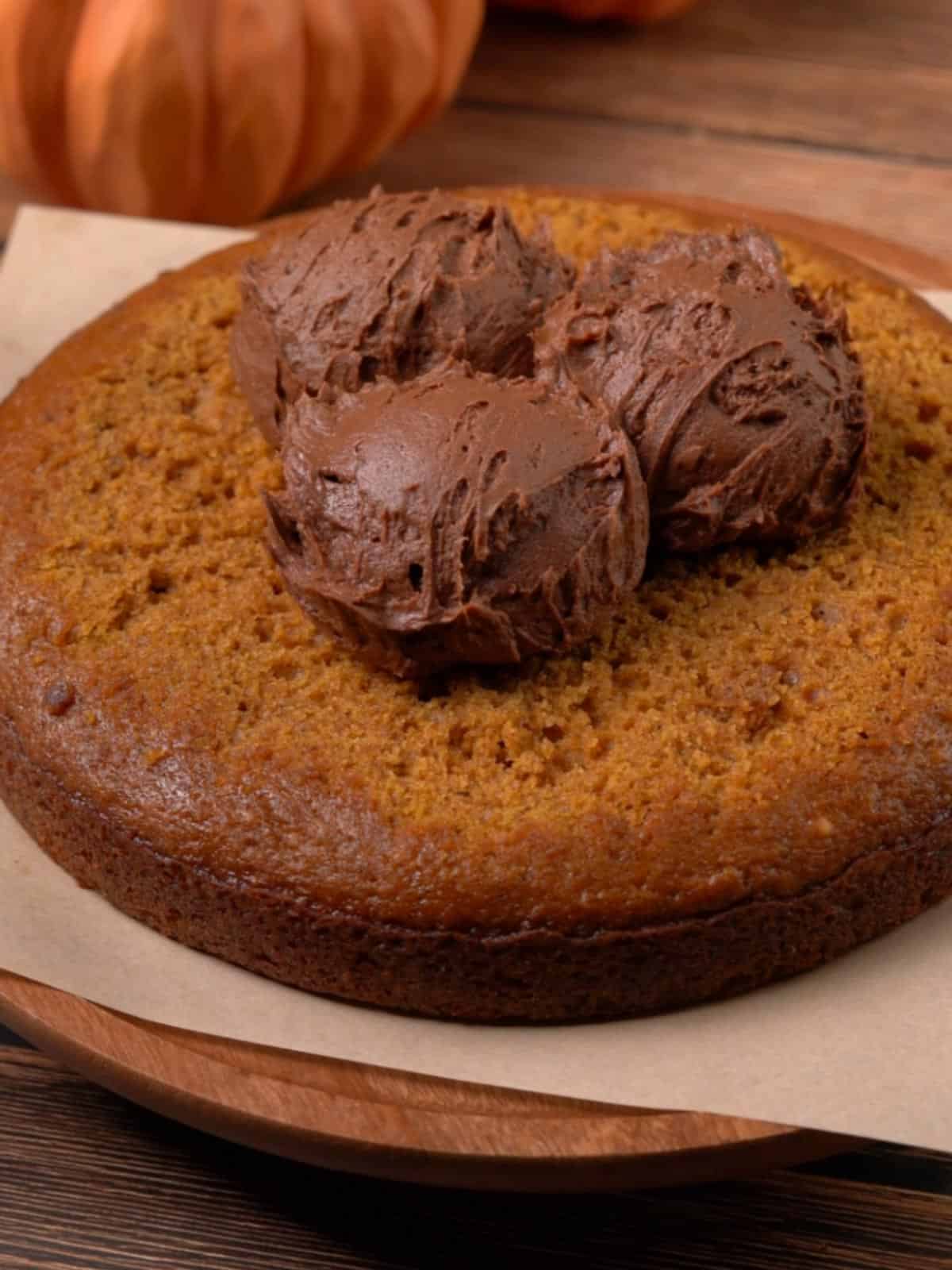 A cake layer with chocolate frosting on top about to be spread.