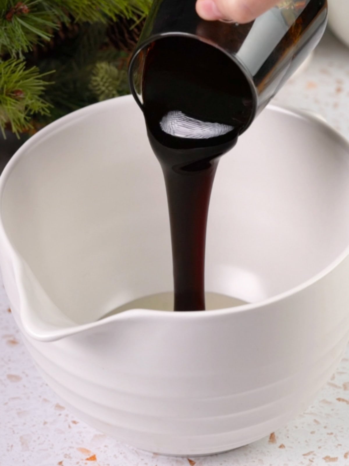 Molasses being added to a bowl on the counter.
