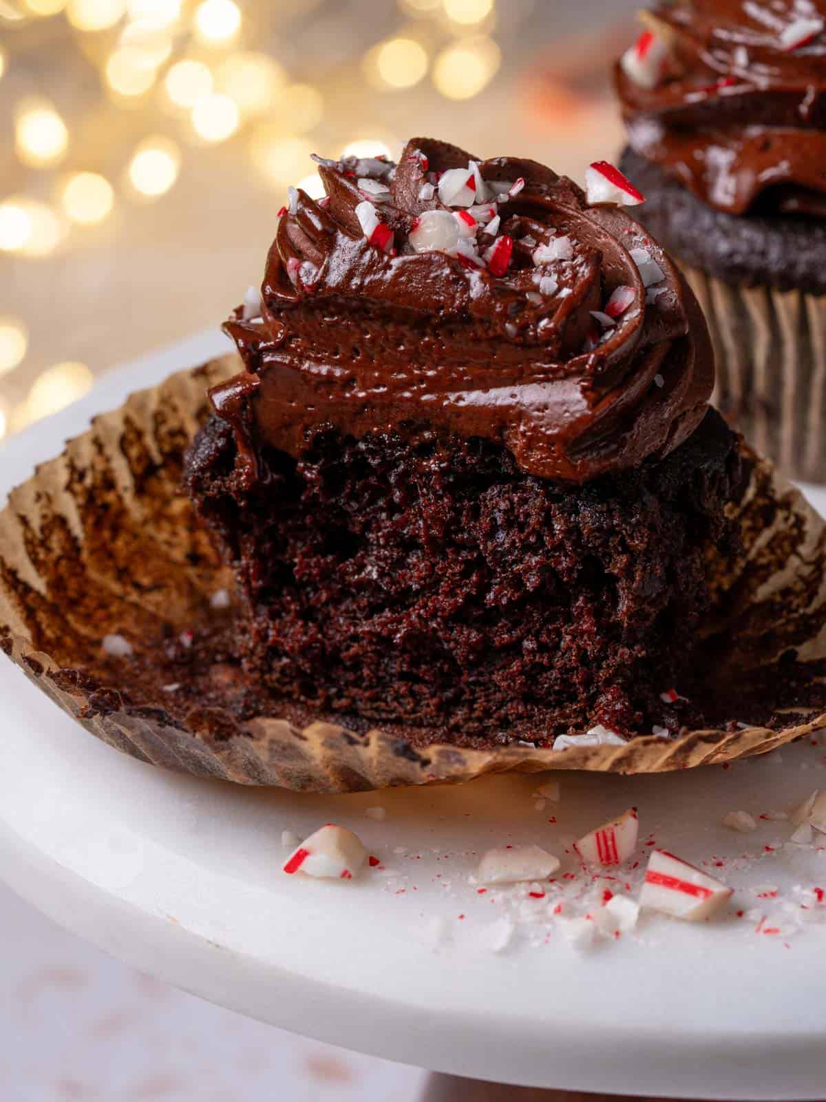 A cupcake on a cake stand with peppermint candies around it.