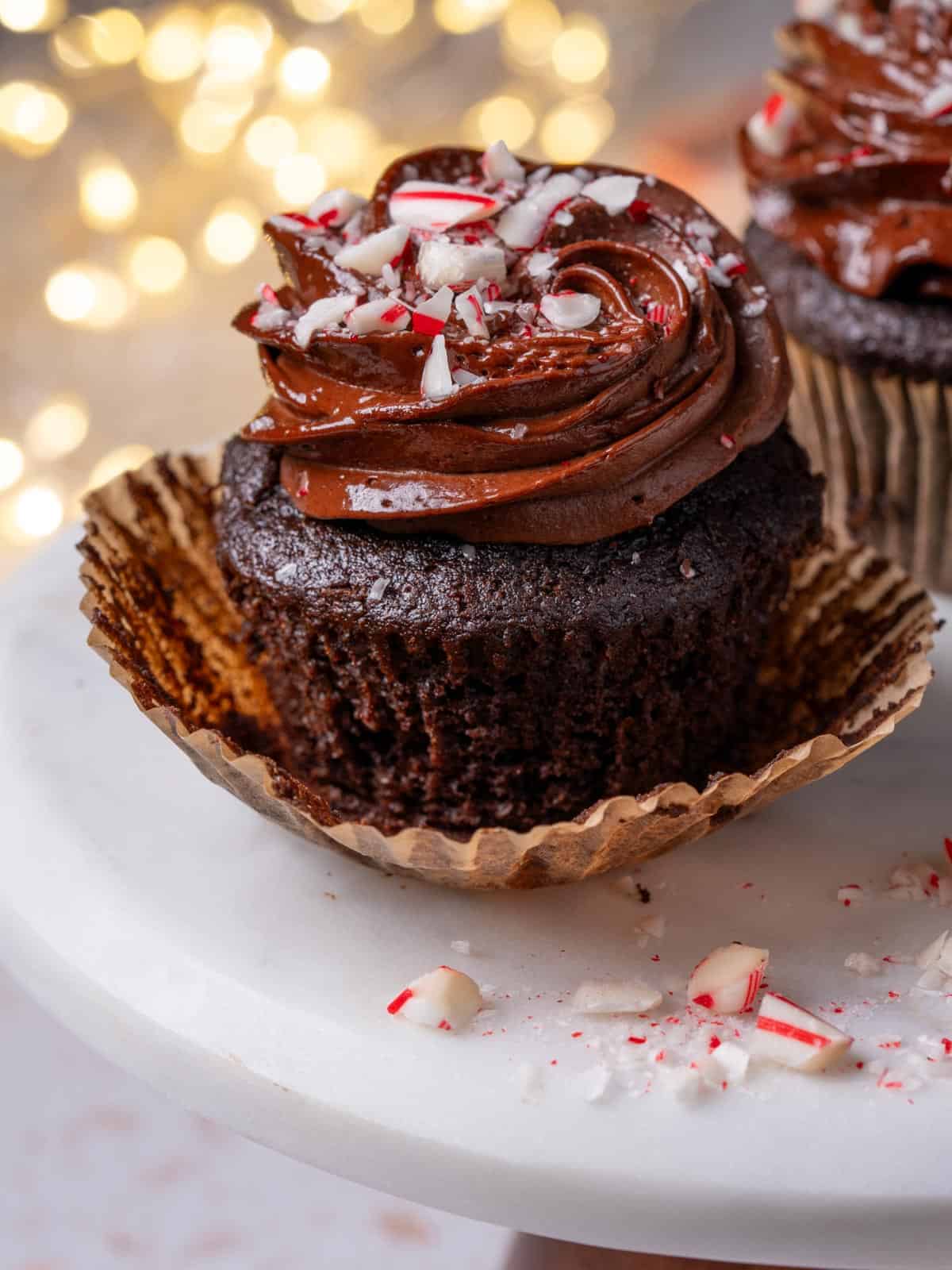 A cupcake on a cake stand with peppermint candies around it.
