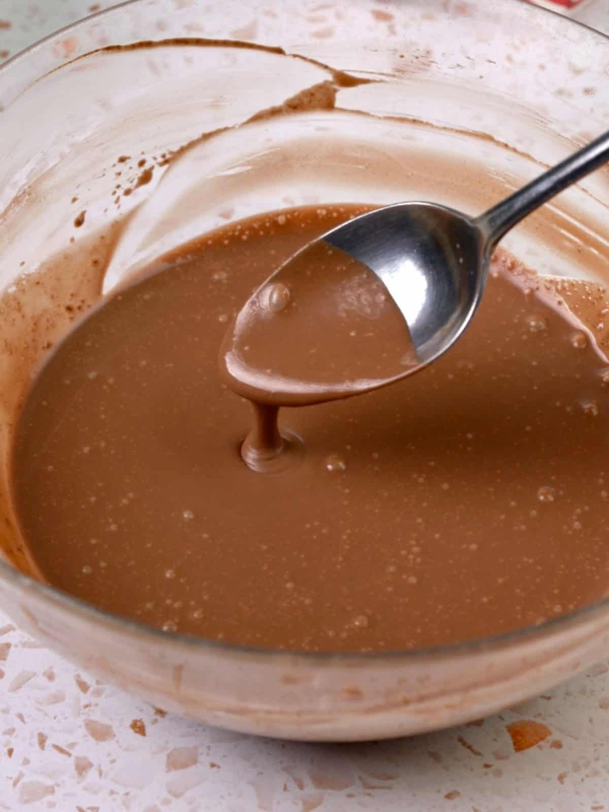 Chocolate and heavy cream mixed until melted together in a bowl.