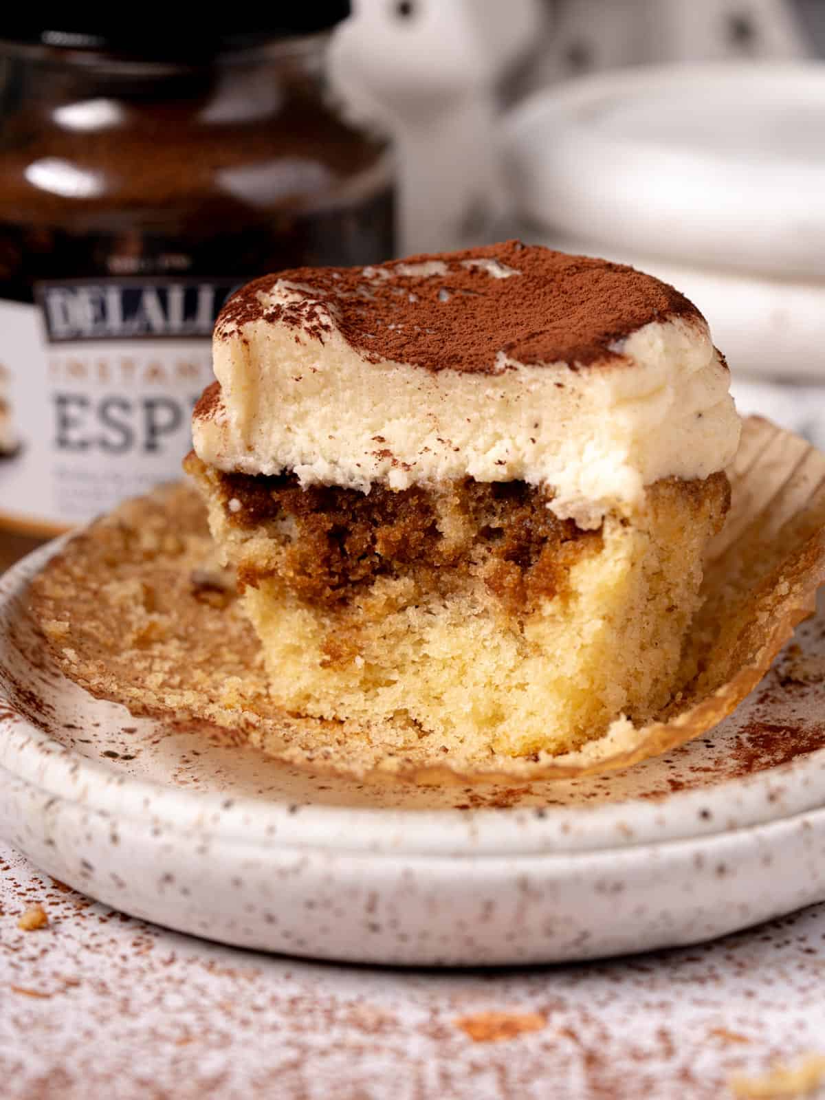 A cupcake with mascarpone frosting and espresso soak on a plate.