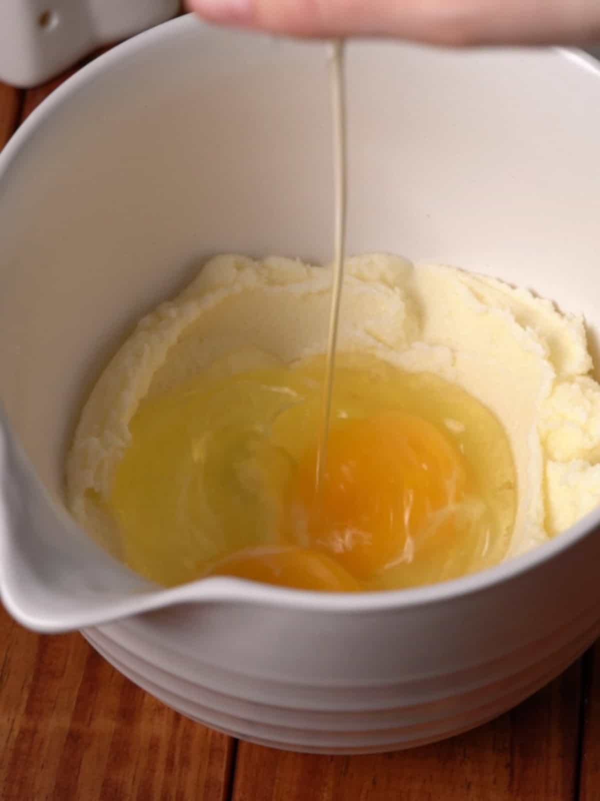Eggs being added into a bowl with sugar and butter.