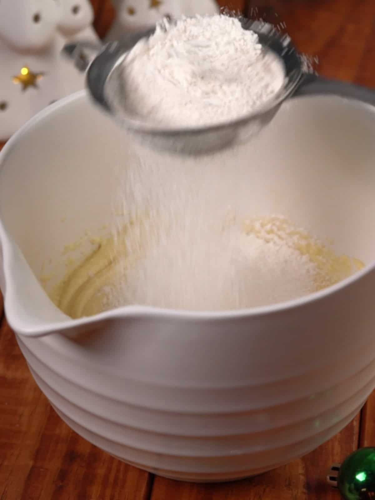 The dry ingredients being added to the wet ingredients in a white bowl.