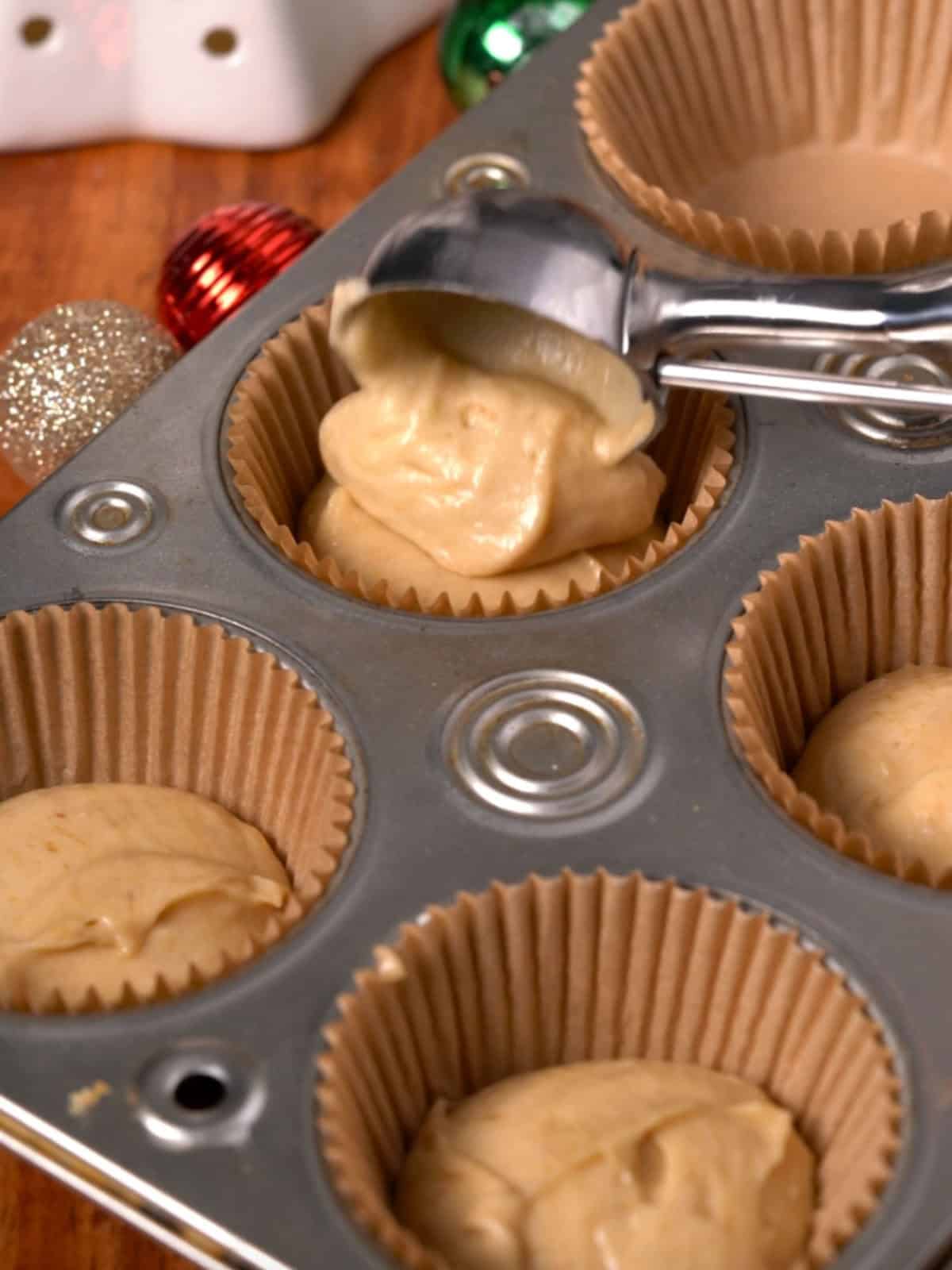 Cupcake batter being added to cupcake liners in a pan.