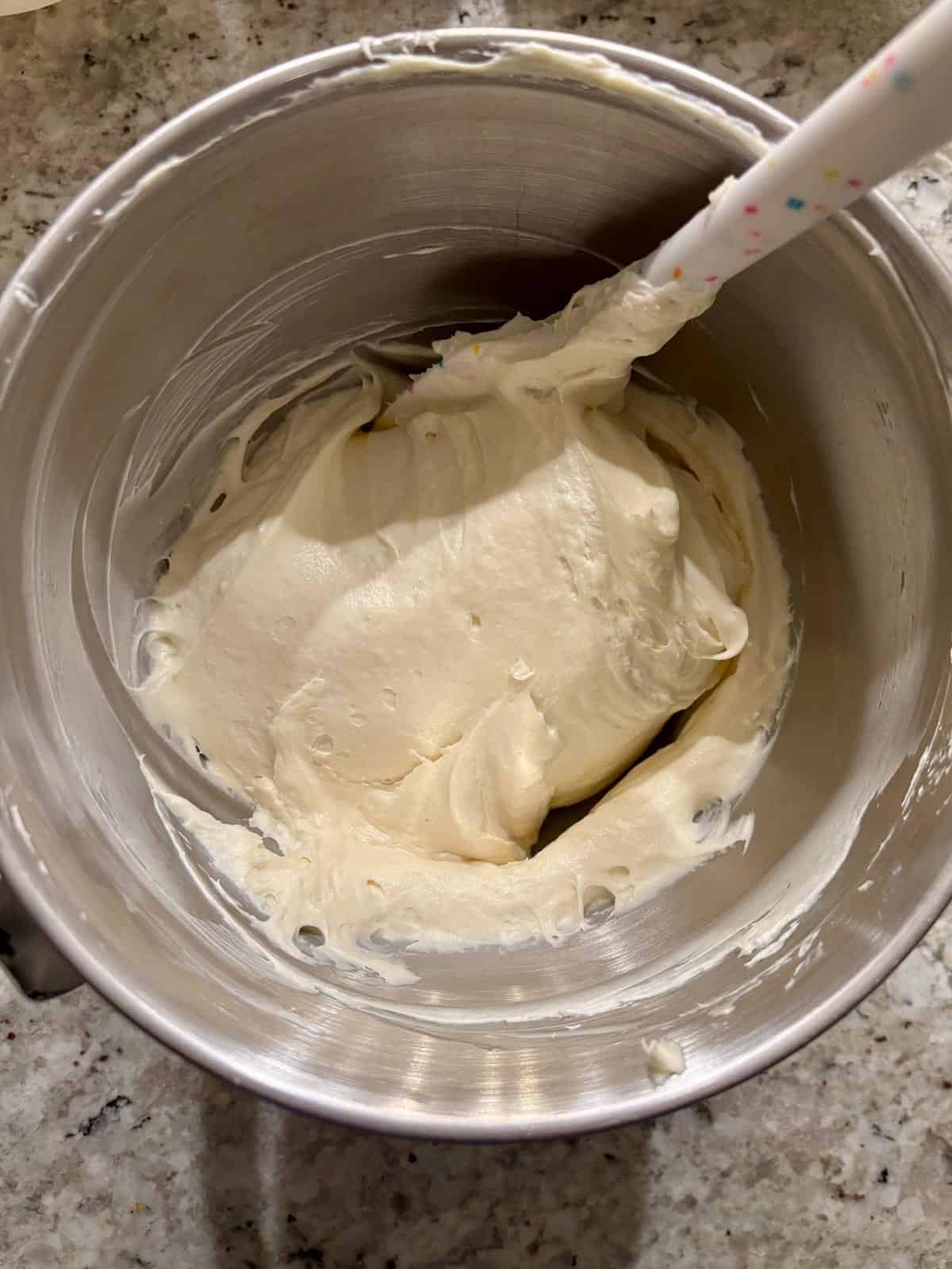 White chocolate, cream cheese, and whipped cream being mixed together.