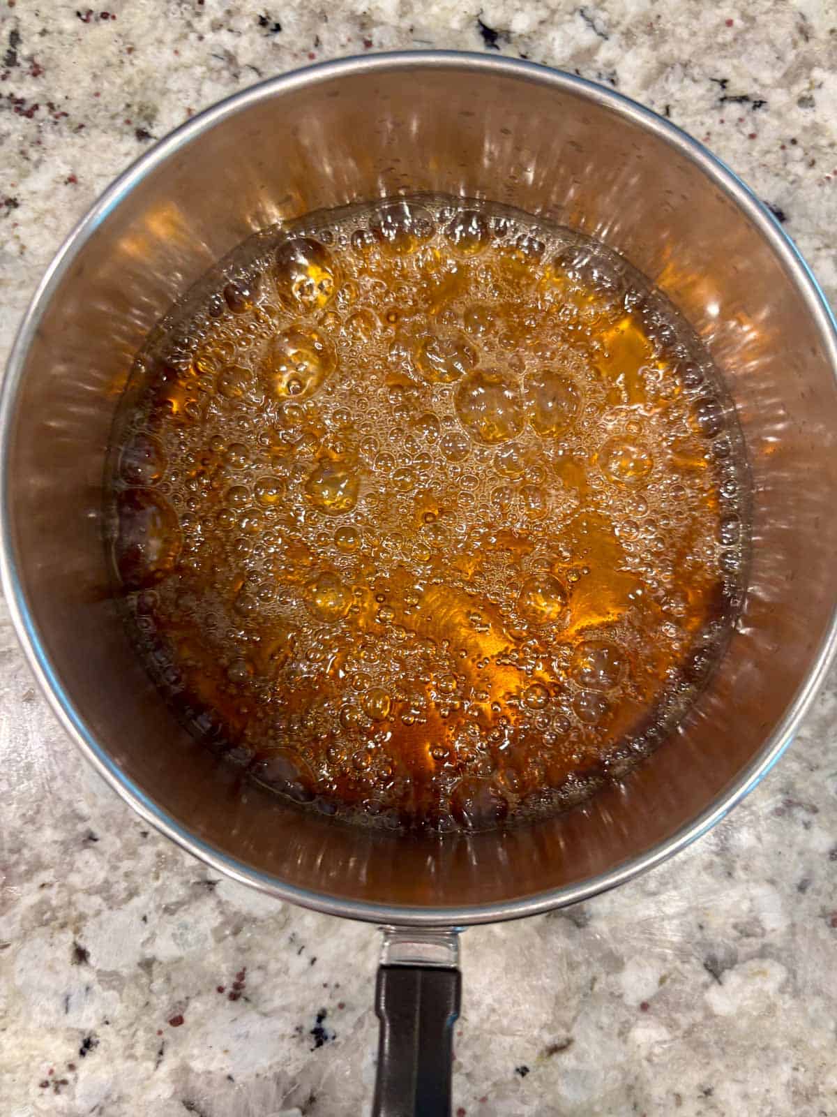 Caramelized sugar in a sauce pan showing the amber color on the counter.