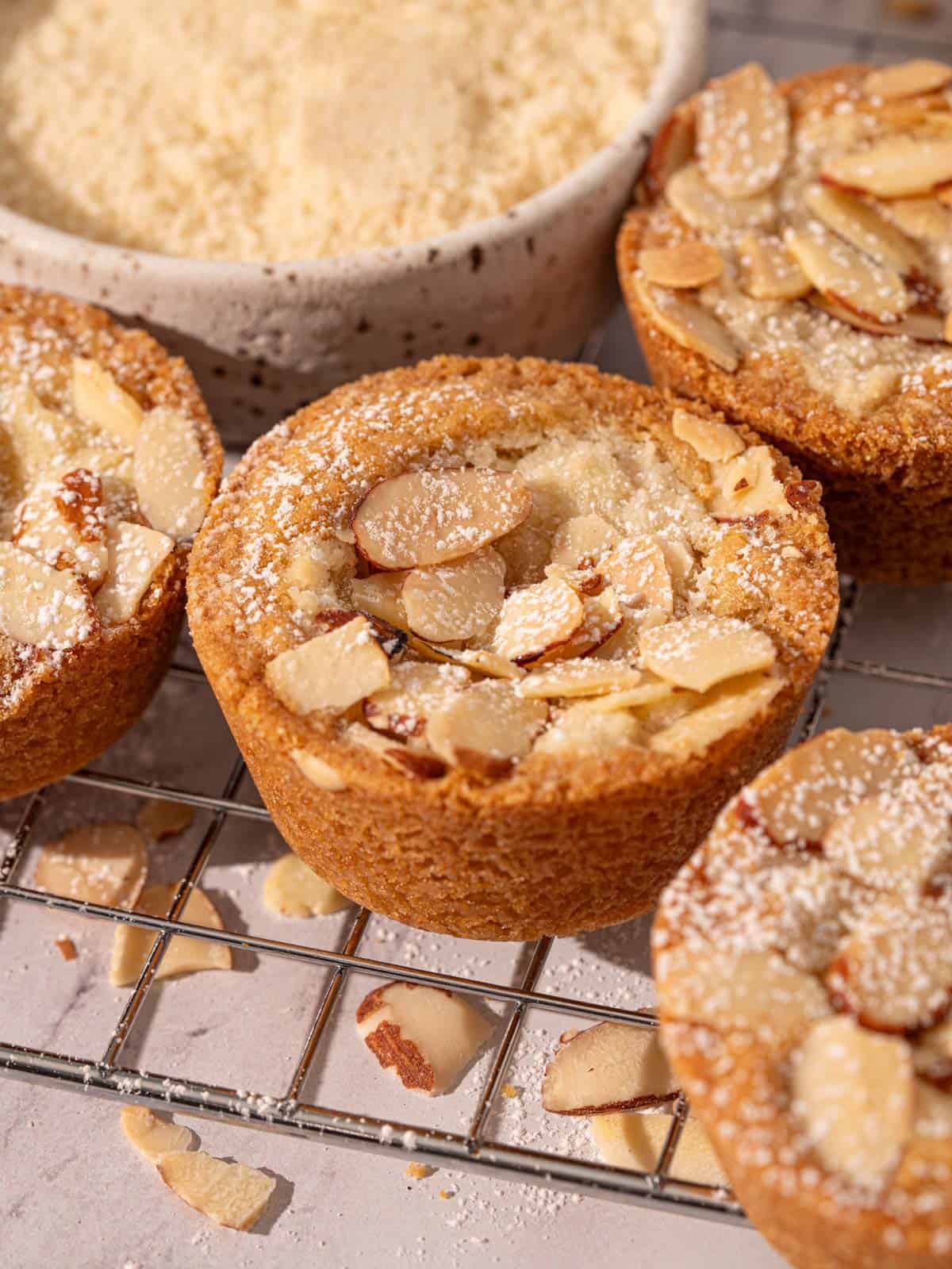 A close up of the cookies on a rack with almonds around them.