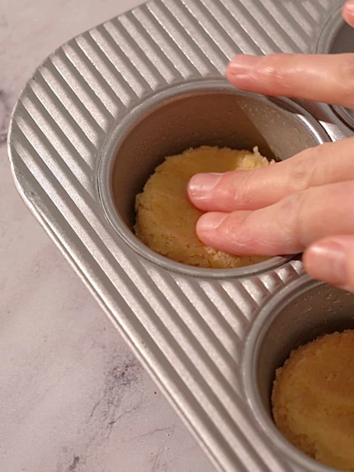 Pushing cookie dough into the pan before the almond filling.
