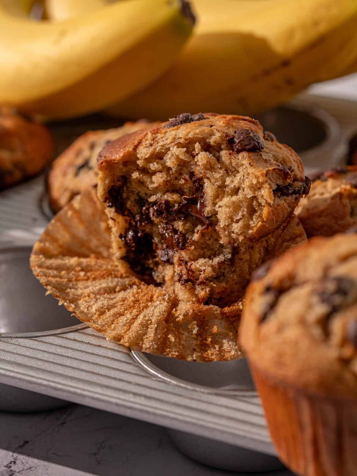 A closeup shot of a banana chocolate chunk muffin on a muffin pan.