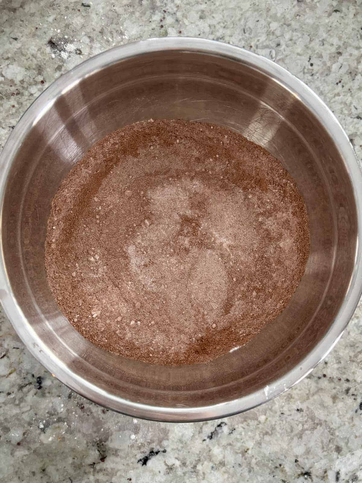 Flour, sugar, and cocoa powder in a bowl being mixed.