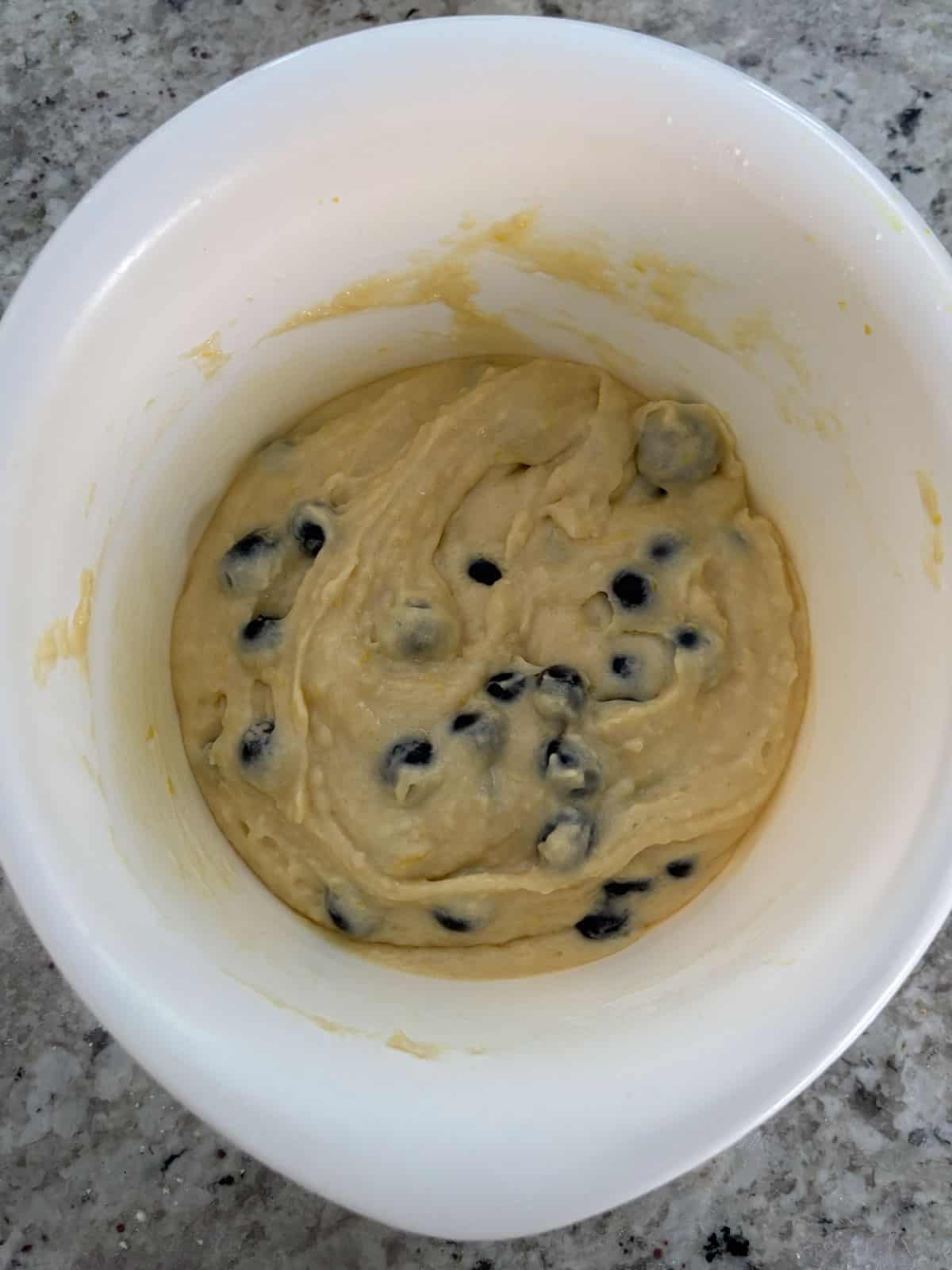 Fresh blueberries being folded into the muffin batter.
