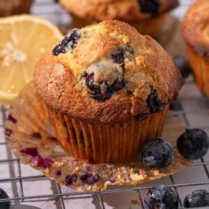 Lemon blueberry muffins on a rack with blueberries around.