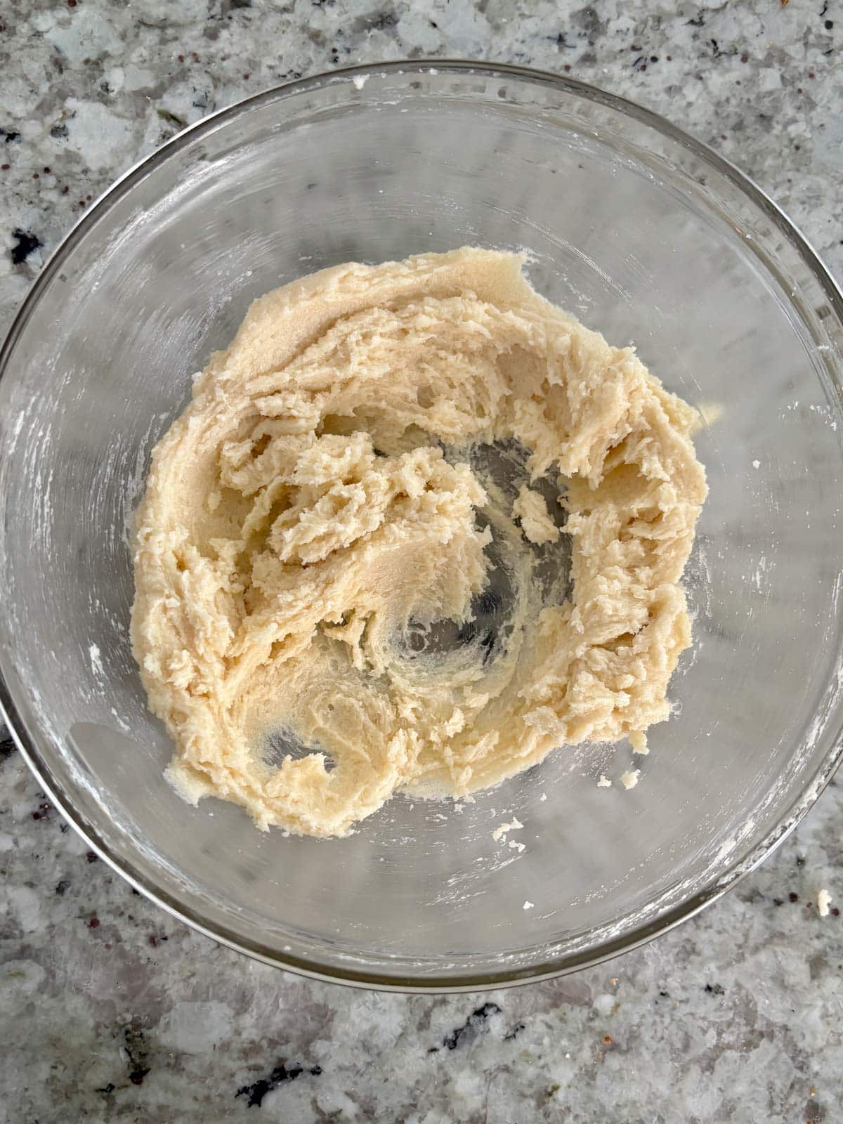 Butter and sugars being creamed in a glass bowl.