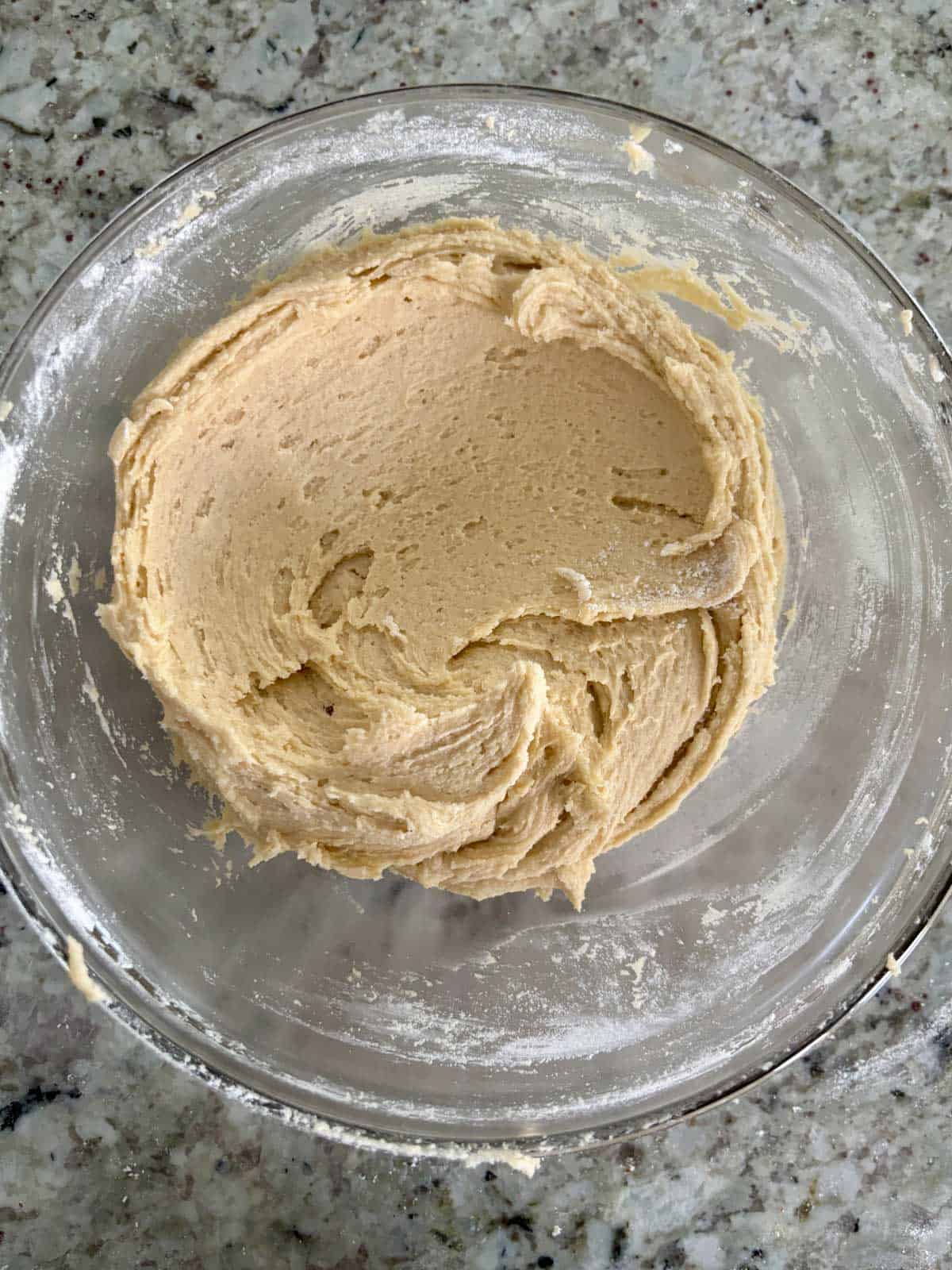 Flouring being added to the mixture and mixed until a dough forms.
