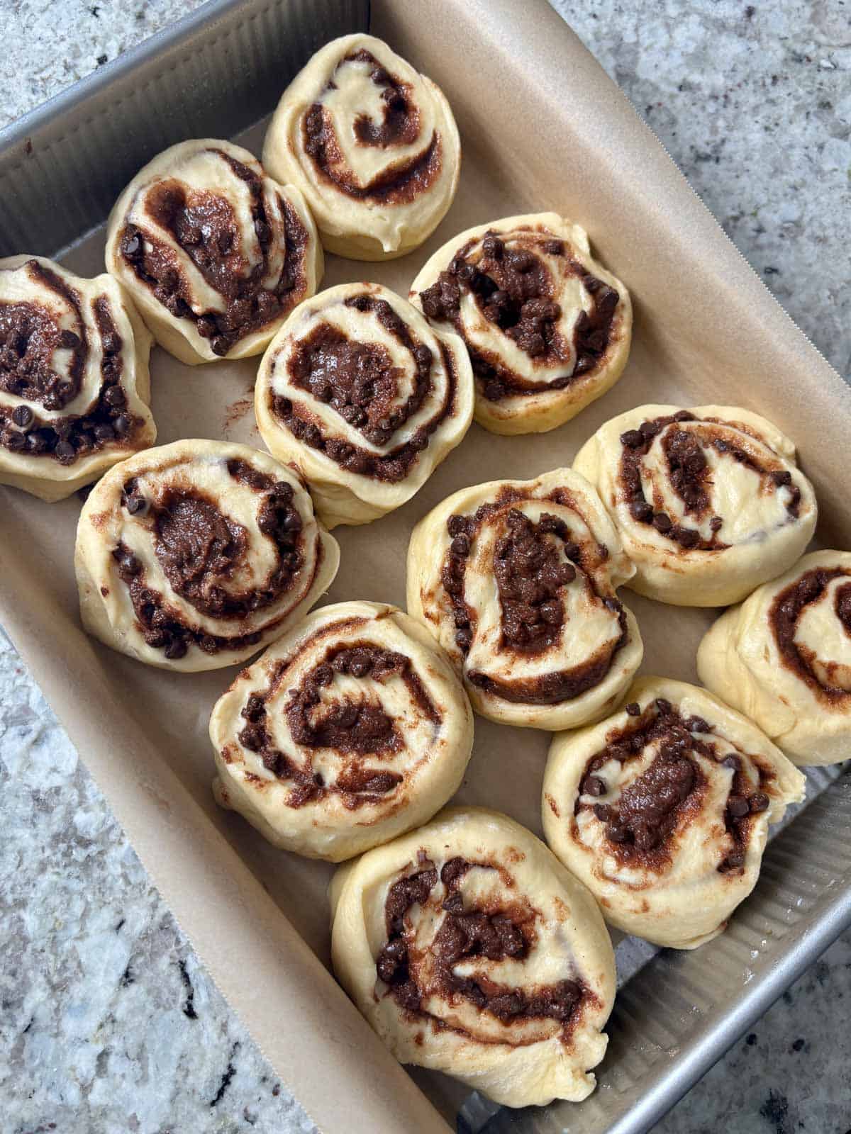 The cut cinnamon rolls in a 9X13 pan with parchment paper.