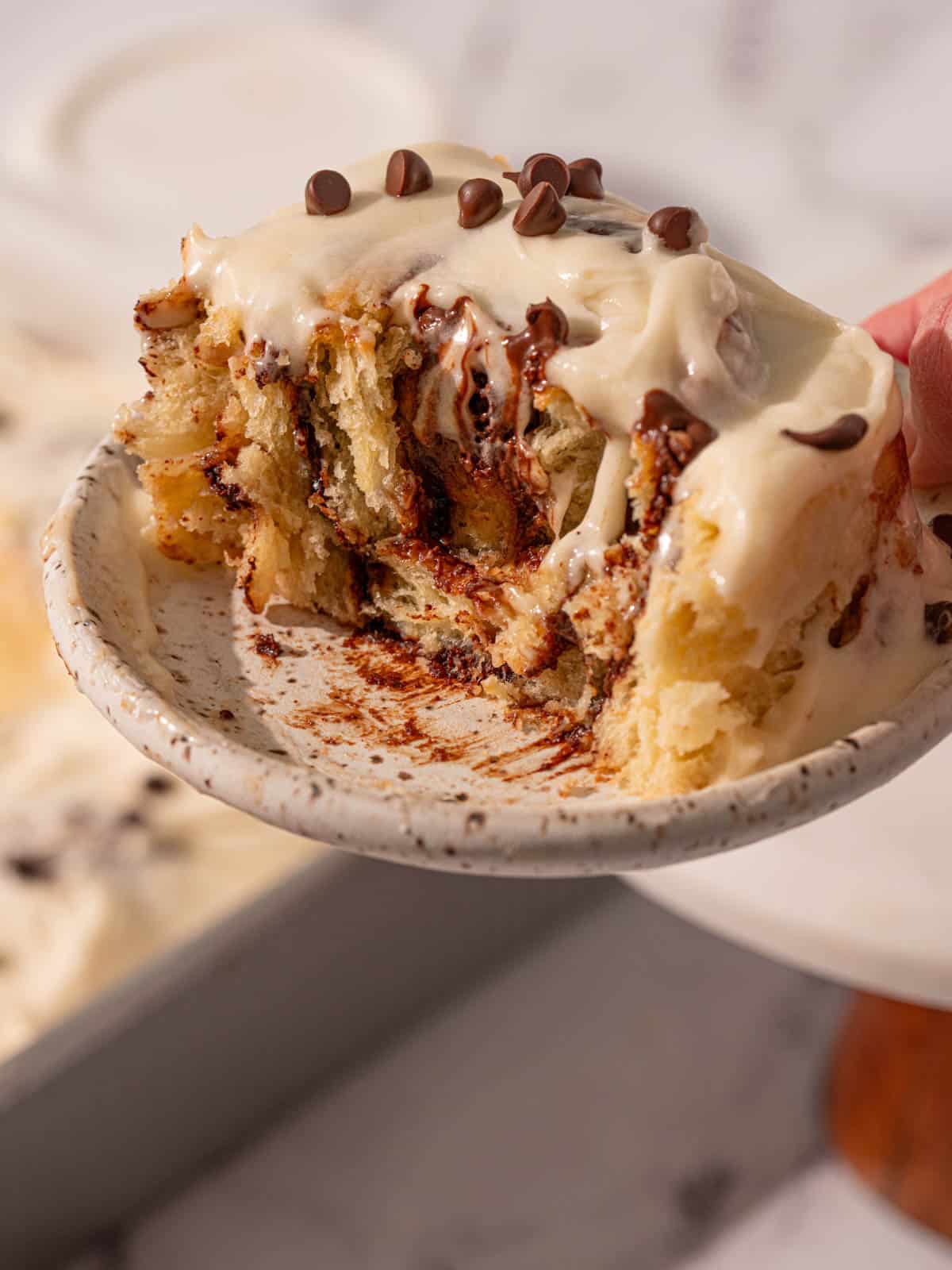 An iced bun with chocolate filling and chocolate chips on top.