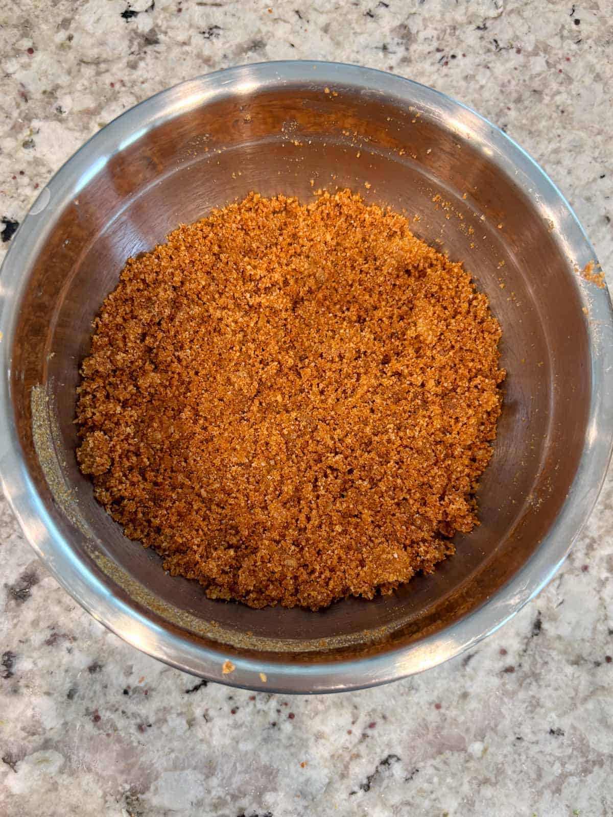 Graham cracker crumbs mixed with sugar and melted butter in a bowl.