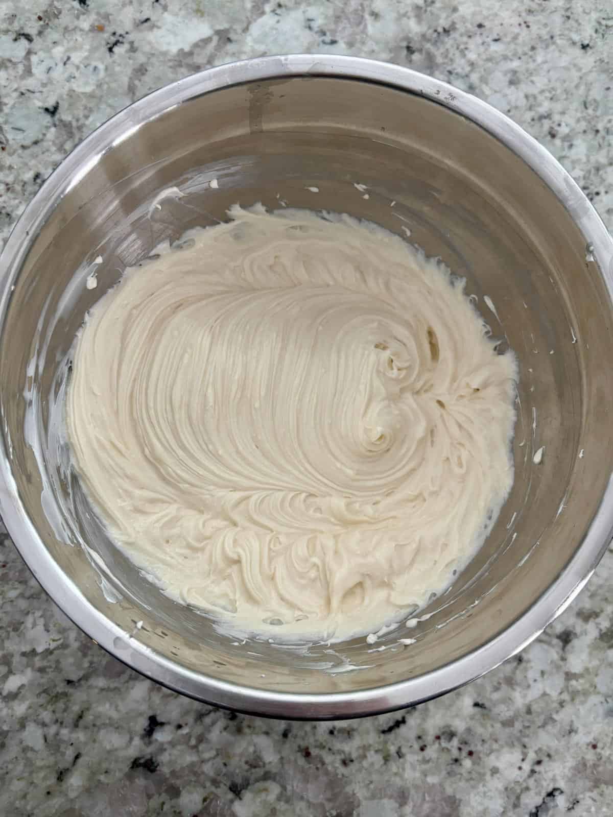 Cream cheese, sugar, vanilla, and lemon being mixed together.