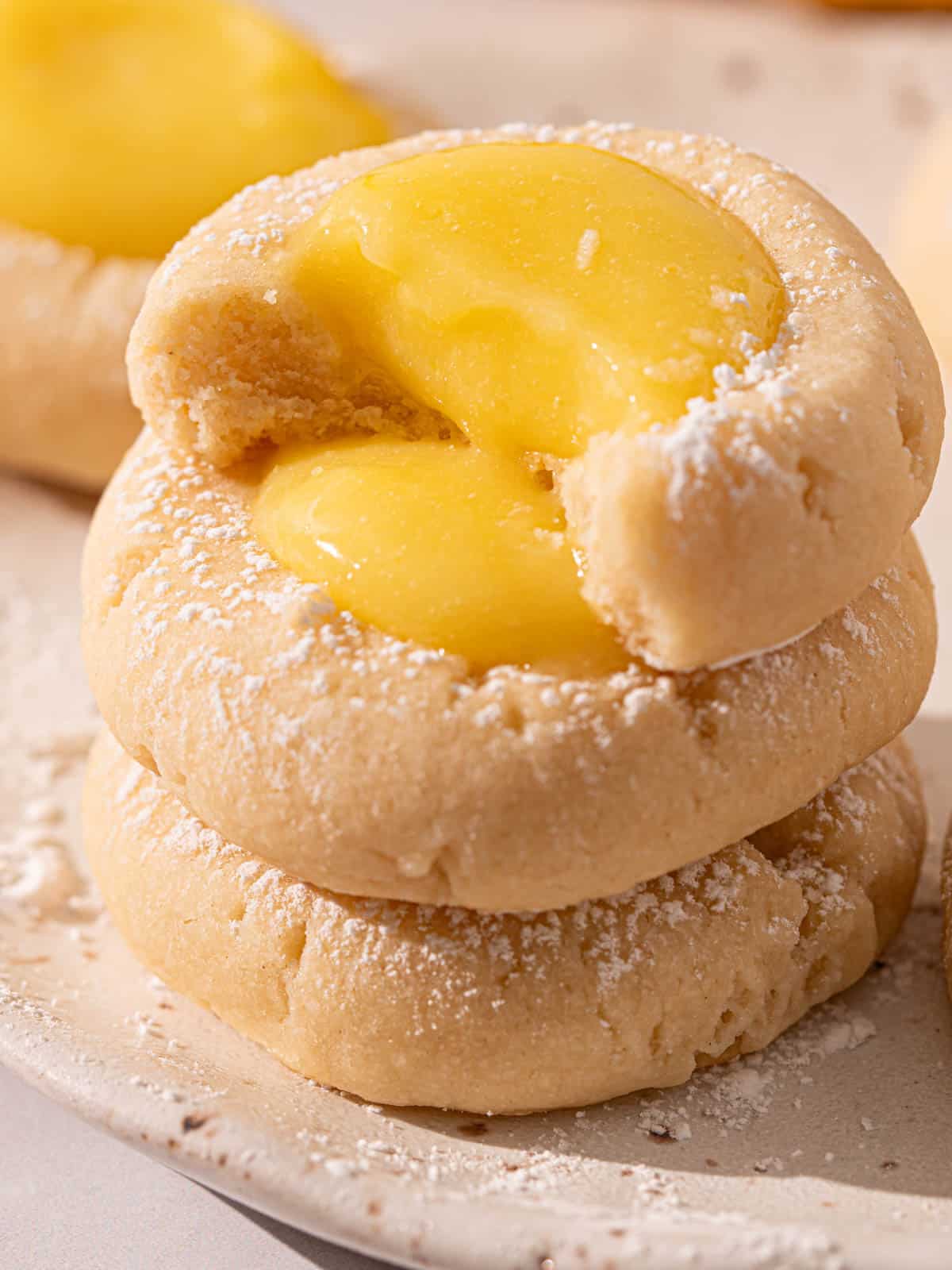 Lemon curd thumbprint cookies stacked showing the texture.