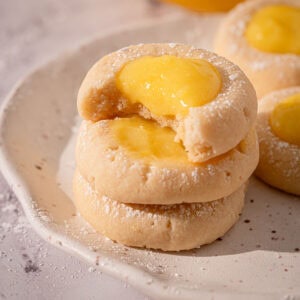 Cookies lemon curd on a plate stacked with powdered sugar.