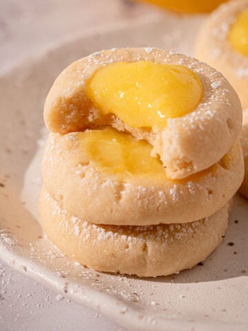 Cookies lemon curd on a plate stacked with powdered sugar.