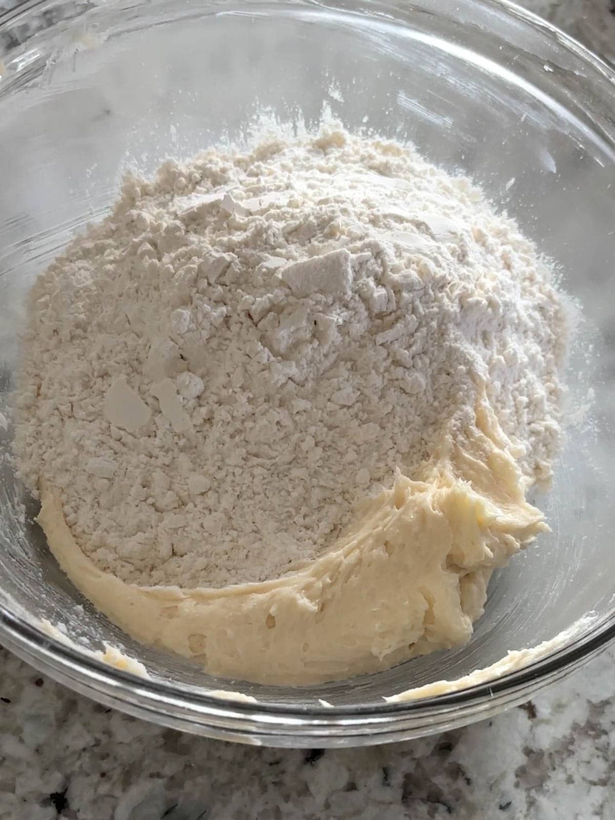 Flour, cornstarch, and salt being added to the butter mixture in a bowl.