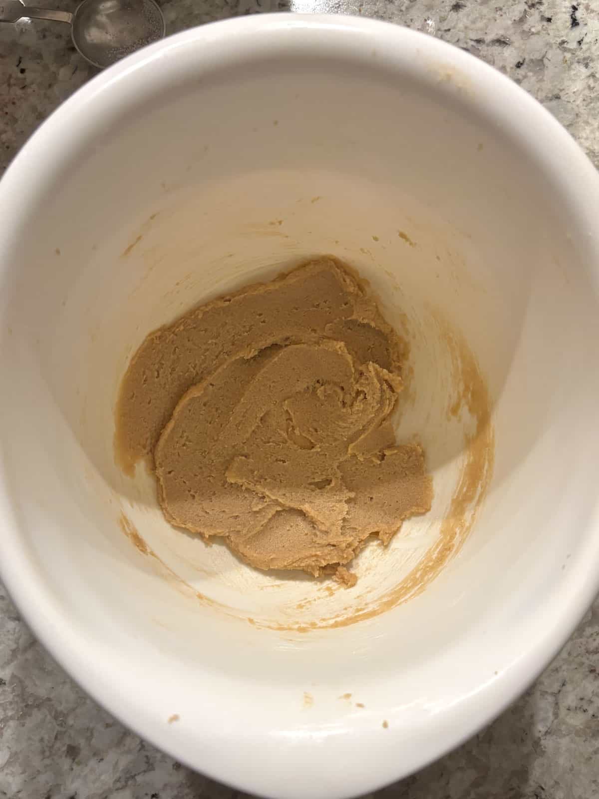 Butter and sugar being creamed together until light and fluffy in a bowl.
