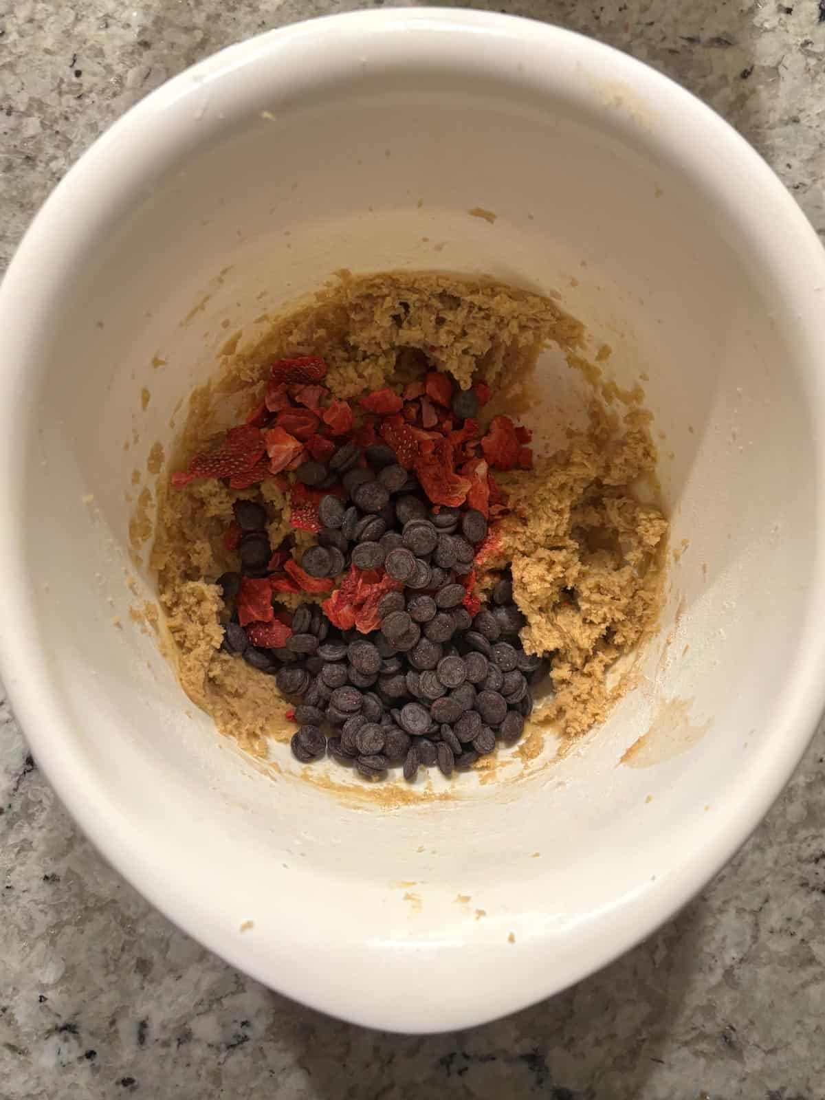 Freeze dried strawberries and chocolate chips being added to the cookie dough.