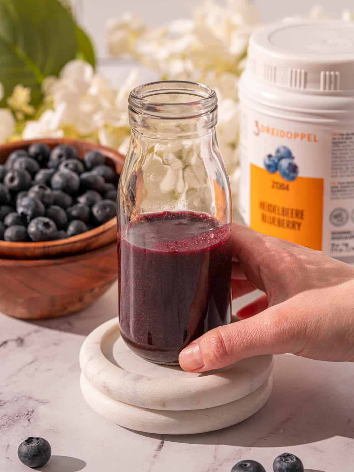 Blueberry syrup in a bottle with blueberries around it.