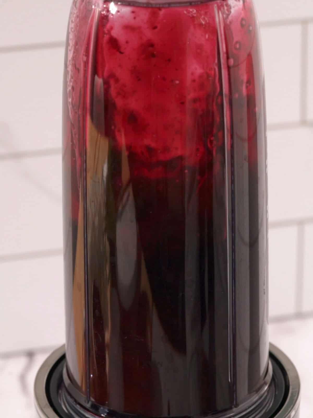 Blueberry syrup being blended up in a blender.