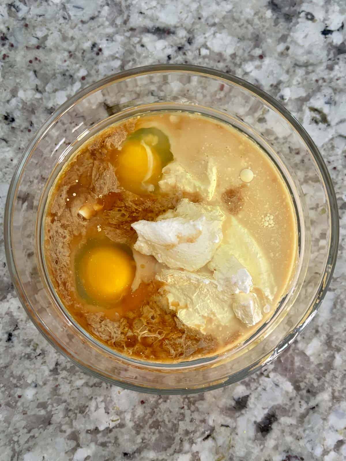 Milk, eggs, sour cream, oil, and vanilla in a glass bowl.