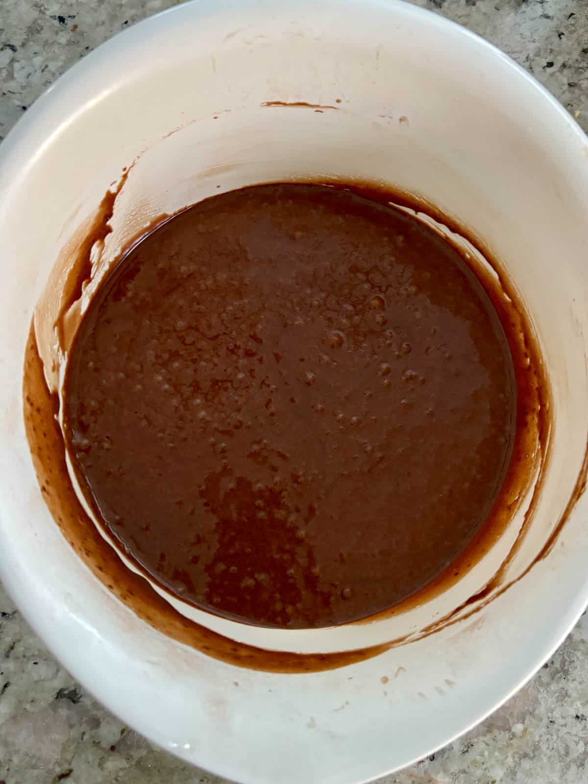 Hot coffee added to make a chocolate cake batter in a bowl.