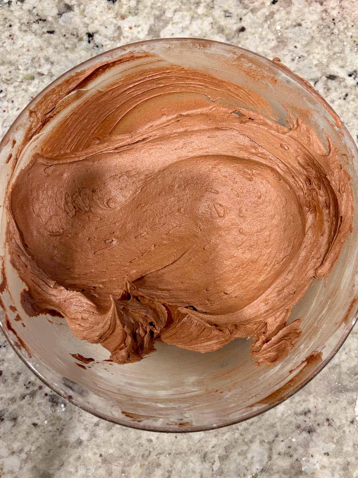 Chocolate buttercream frosting in a bowl on the counter.