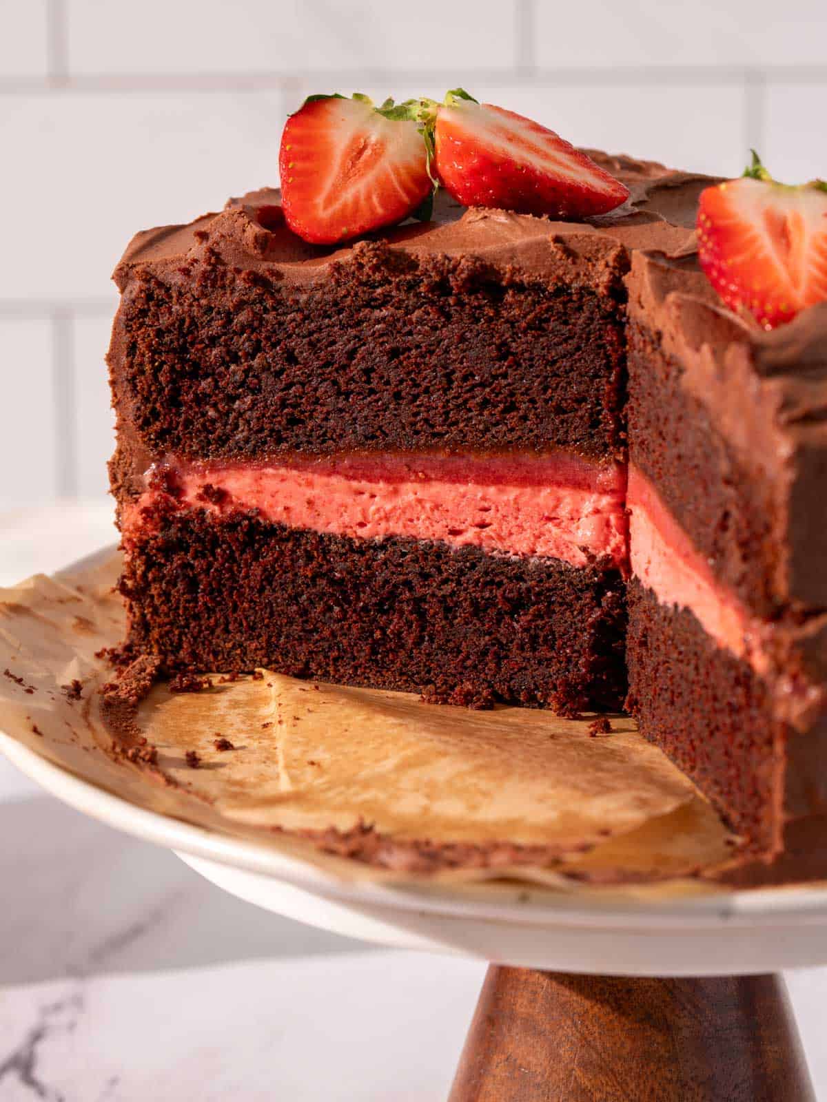 Chocolate cake with strawberry filling and chocolate frosting on a cake stand.