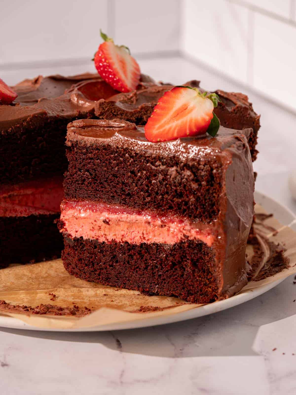 Chocolate strawberry cake on a plate with fresh strawberries on top.