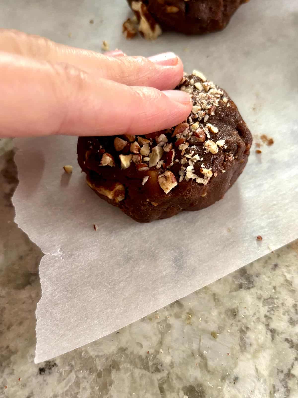 Pushing down the cookie dough ball to flatten it slightly.