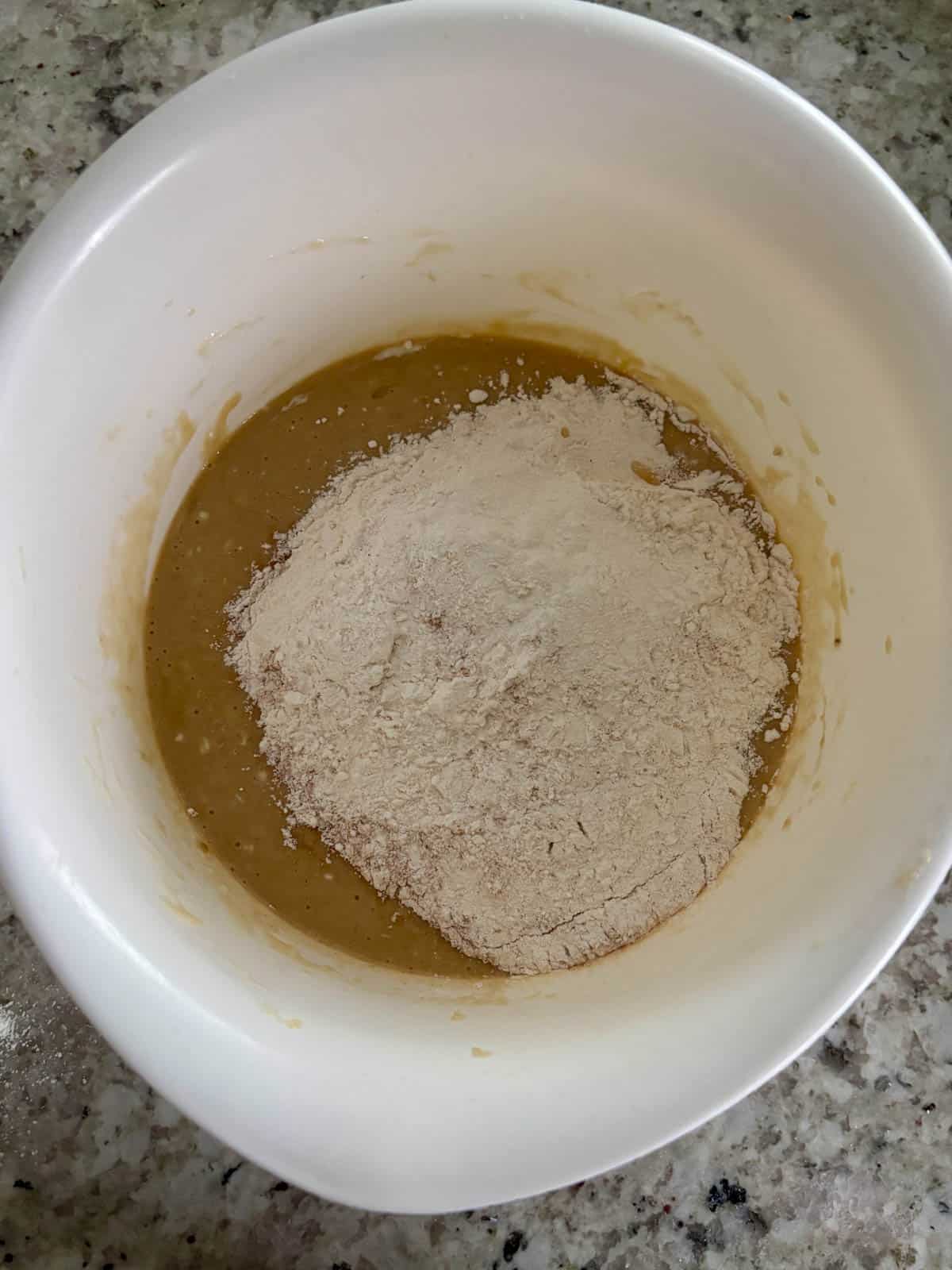 All purpose flour, cinnamon, kosher salt, and baking powder being added to the wet ingredients.