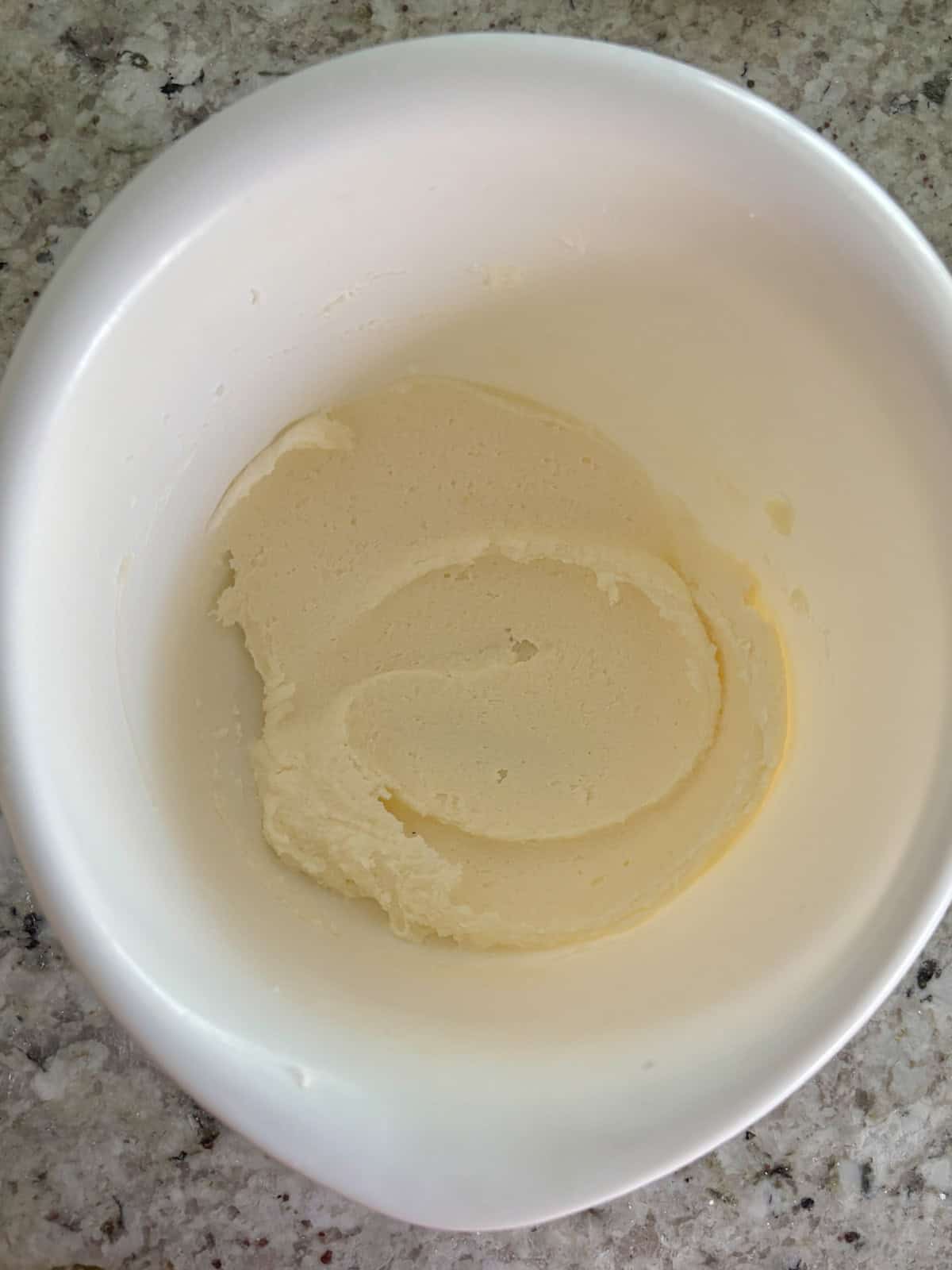 Butter and sugar being creamed together in a white bowl.
