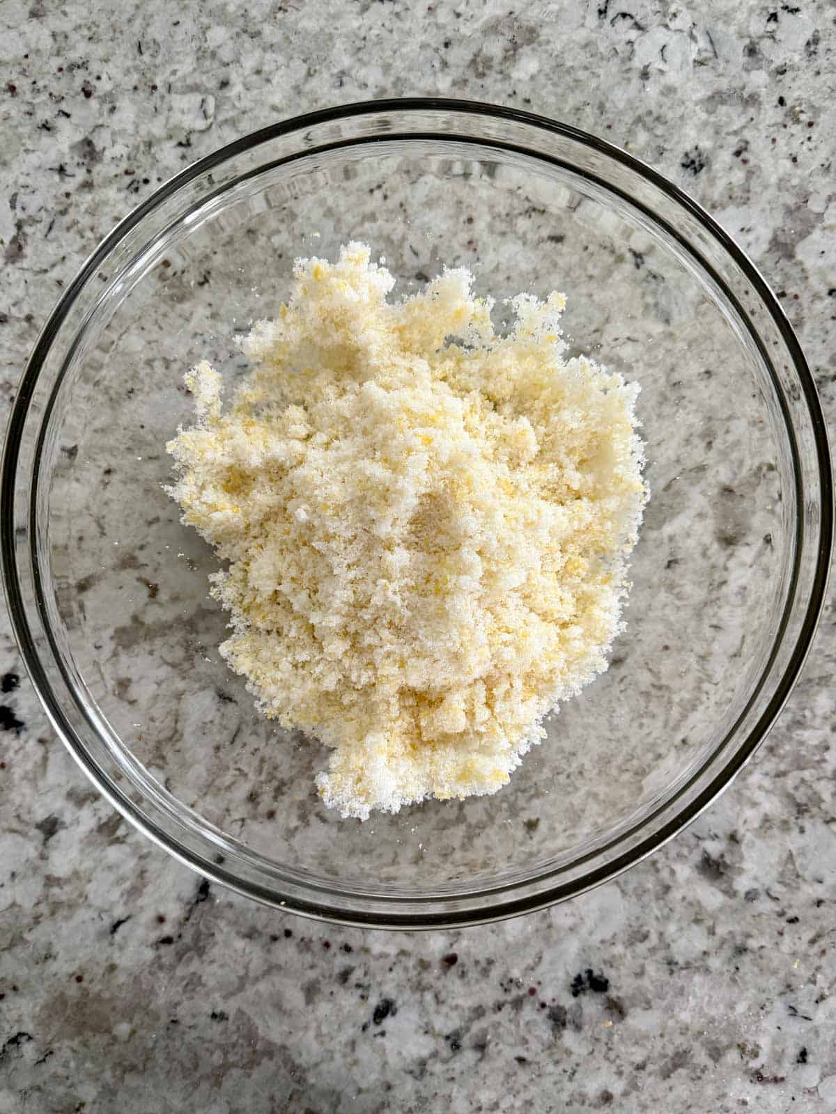 Lemon zest and granulated sugar in a bowl after being rubbed together.