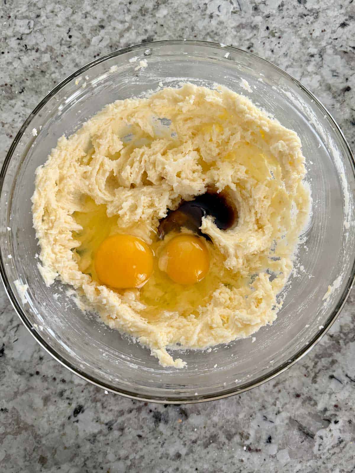 Eggs and vanilla being added to the creamed butter sugar mixture.